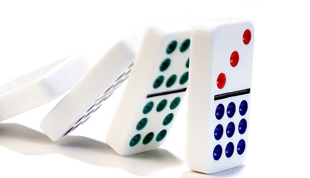 Dominoes falling against each other on a white background stock photo