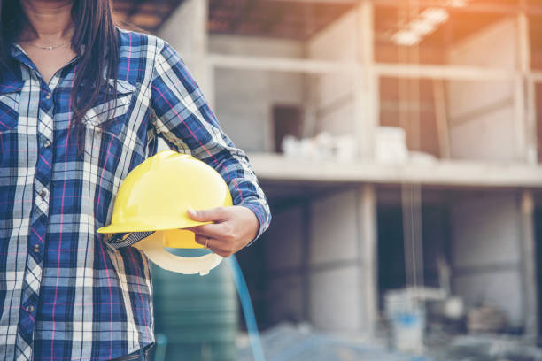Woman engineer working on construction site and holding yellow hard hat safety helmet head protection at manufacturing industry. Construction Concept. stock photo