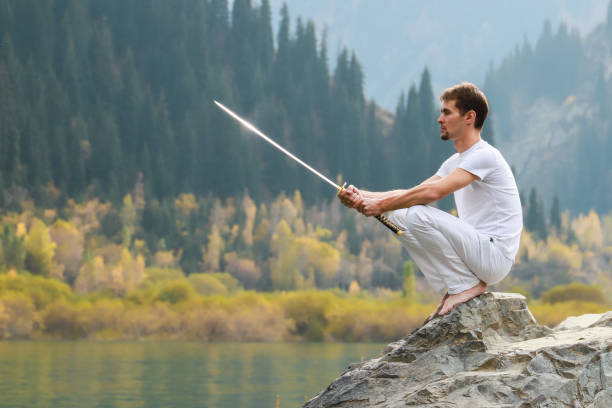 istock A wise man sits on a stone and holds a sword in his hands. Mountain Lake background 1211216063