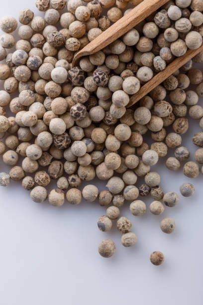 istock white peppercorns in wooden scoop on white background 1211216183