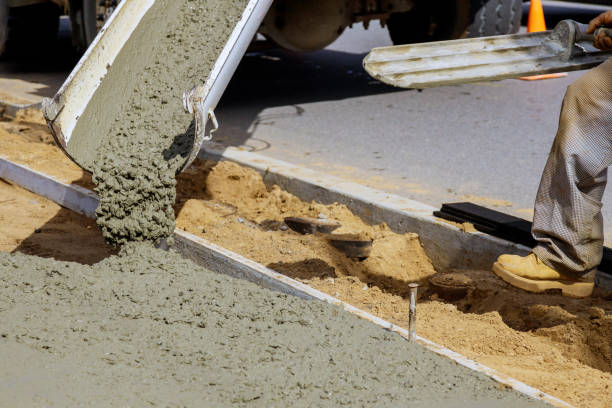 istock Construction worker pour cement for sidewalk in concrete works with mixer truck with wheelbarrow 1211217569
