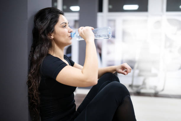 istock Young woman in the gym drinks water 1211217737