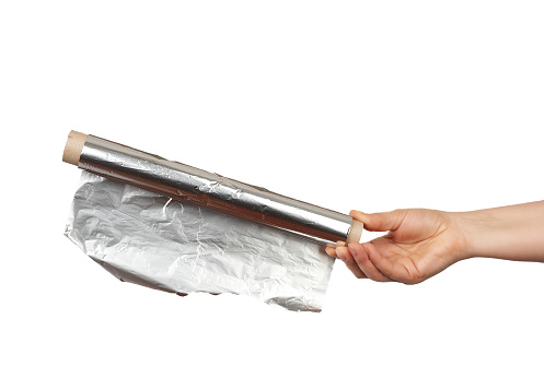 hand holds a roll with twisted gray shiny foil on a white background, food packaging