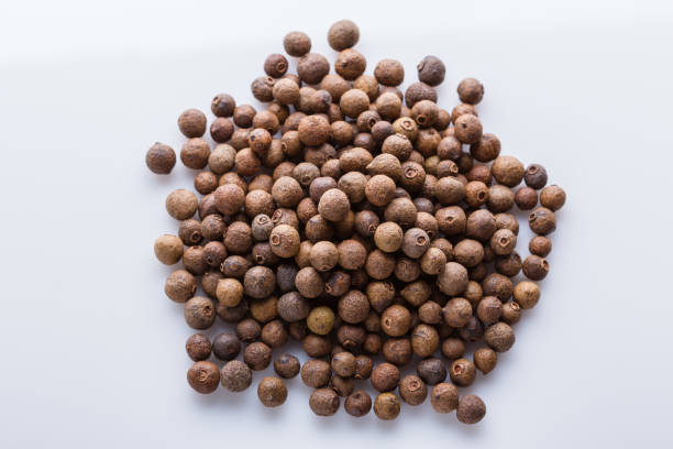 Allspices or Jamaica pepper in jar on white background. Closeup.