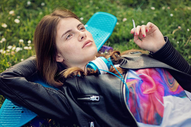istock Nostalgic young girl is lying down and smoking cigarette 1211224645