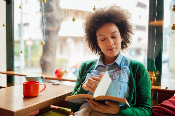 istock Young woman with curly hairstyle reading a book 1211226747
