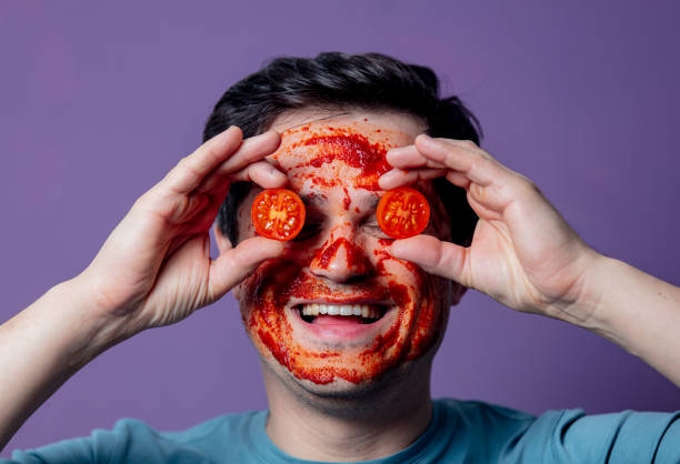 smiling guy in a tomatoes face care mask stock photo