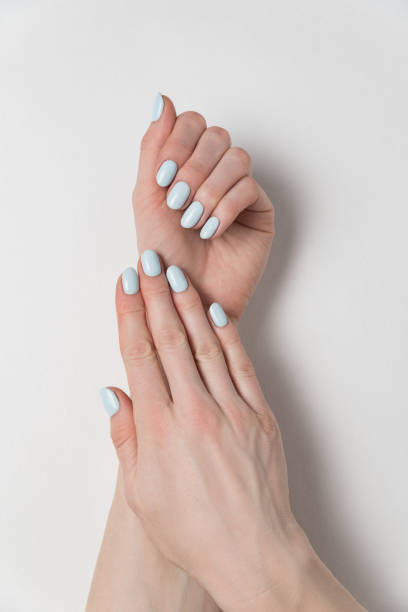istock Female hands with delicate blue manicure. Gel Polish. White background. Verrical frame 1211229906
