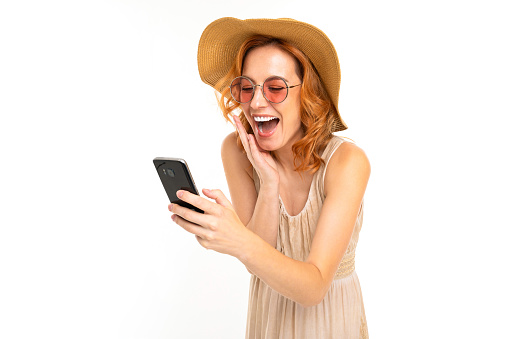 beautiful girl in a summer hat and sunglasses orders tickets on the phone on a white background.