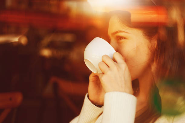 istock A young girl is drinking coffee with reflection behind the window 1211237871