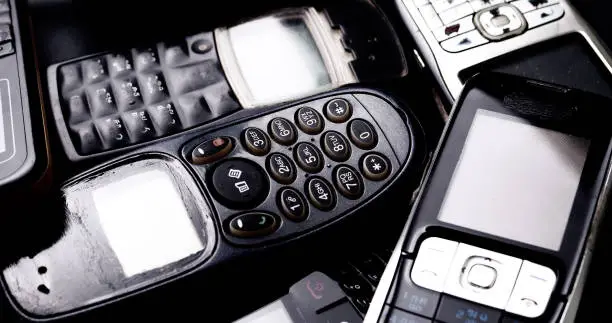 Heap of vintage mobilephones on a black background.