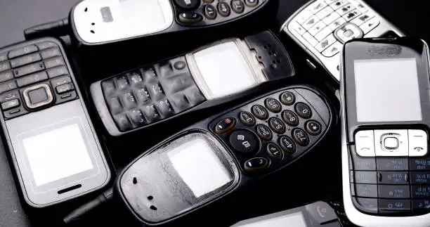 Heap of vintage mobilephones on a black background.