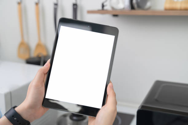 istock Close-up of hand holding digital tablet at home in kitchen. 1211248294