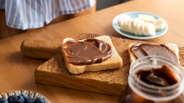 Chocolate nut butter toast on a wooden board. Tasty breakfast or lunch sandwich