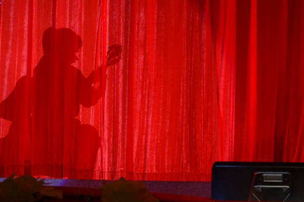 istock The silhouette a man shadow playing a classic guitar on the red curtain. 1211260103