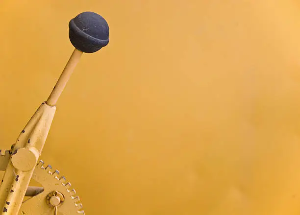 This gear shifting lever is on an old yellow tractor and the yellow background one of the fenders. Copy space