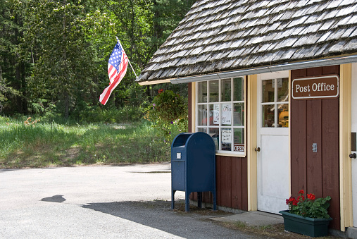 A small shaked roof rural post office flying the stars and stripes.