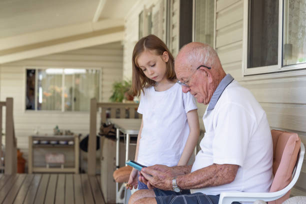 istock Granddaughter and grandfather playing on digital tablet together 1211267378