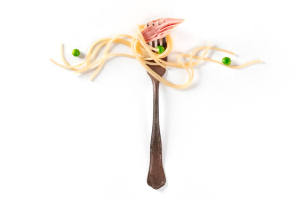 Italian pasta design. A vintage fork with spaghetti, tuna, and green peas, on a white background with copy space