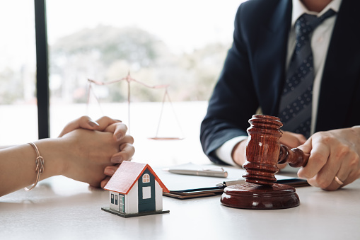 Real Estate Law concept. Gavel on sounding block in hand's Male judge at a courtroom, working for the insurance compensations. report the case on table in modern office.