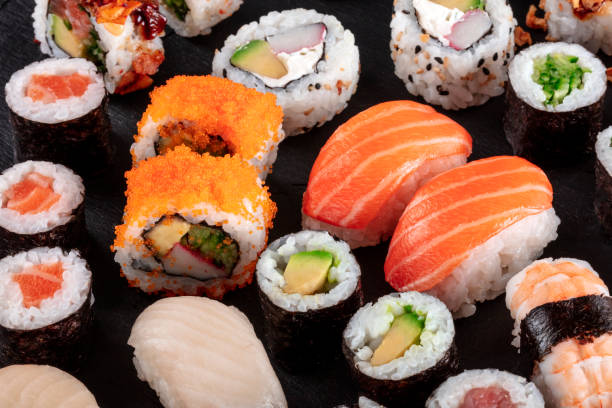 duże sushi ustawione na czarno. asortyment różnych maki, nigiri i rolek - sushi california roll salmon sashimi zdjęcia i obrazy z banku zdjęć