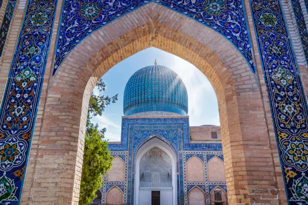 Archway view through ornamental Iwan towards the famous Gur Emir - Amir Temur Mausoleum - Gur e Amir Mausoleum where the famous conqueror Timur also known as Tamerlane was buried in the city of Samarkand, Silk Road, Uzbekistan, Central Asia