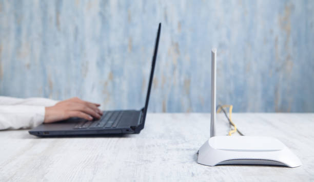 istock Internet router in the desk. Girl using laptop 1211269522