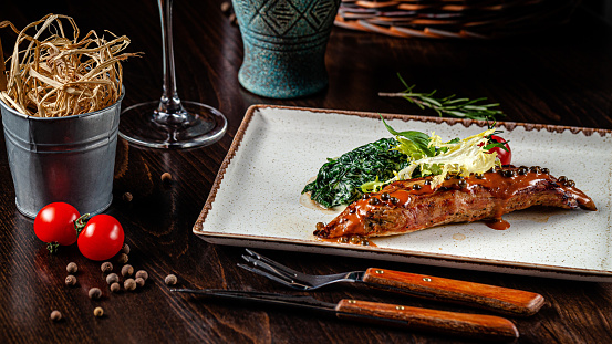 Spanish cuisine. Veal steak with spinach and cream. Red wine is on the table. girl holding in hands a knife and a fork in a restaurant. background image, copy space text