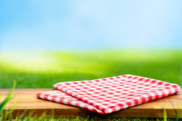 istock Red checked tablecloth on wood with blur green courtyard background.Summer and picnic concepts.Design for key visual food and drink products 1211269648