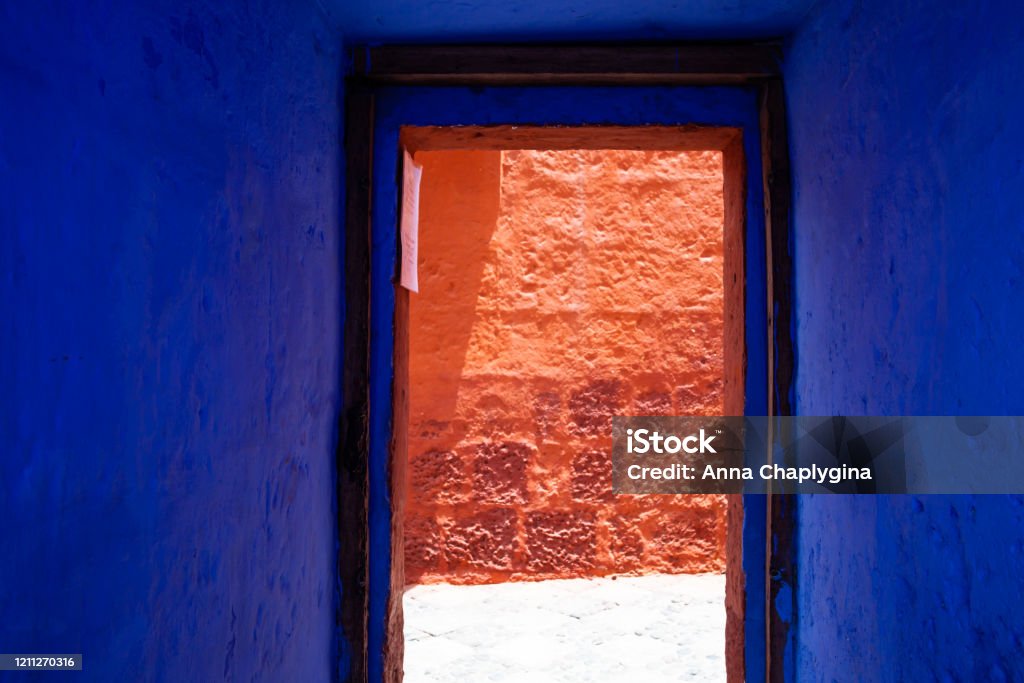 Blue, indigo, doorway overlooking the red wall Blue doorway overlooking the red wall, bright red wall on a sunny day Architecture Stock Photo