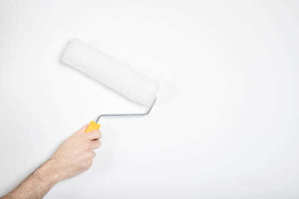 istock The guy holds a roller in his hand. White wall, repair. Builder 1211272211