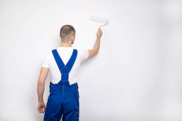 istock The guy paints the wall with a construction roller. Repair. A handsome young guy. Builder 1211272270