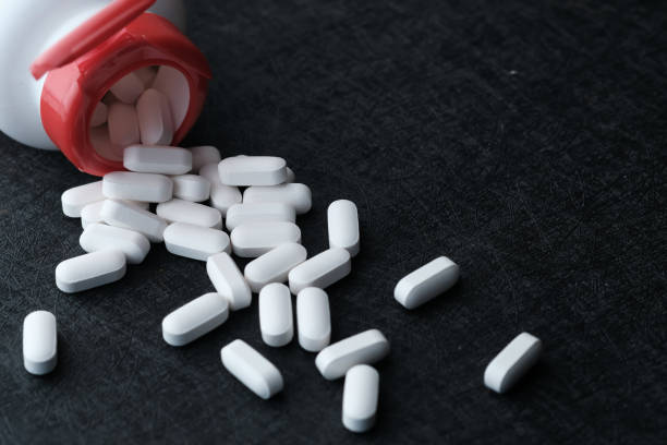 istock close up of white pills spilling from container 1211274737