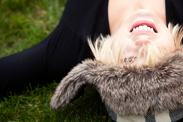 Woman Wearing Lumberjack Hat Attractive and young blond female laying on her back looks up through messy hair while wearing a lumberjack hat. black hat upside down stock pictures, royalty-free photos & images
