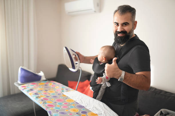 istock Young father ironing clothes and carrying his little daughter 1211277084