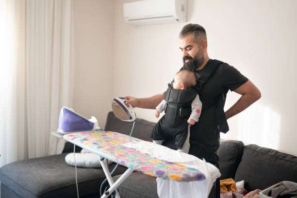 istock Young father ironing clothes and carrying his little daughter 1211277086