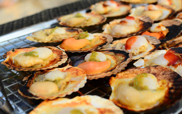 istock Closeup of seared scallop shells with butter on a framing stove. 1211277318