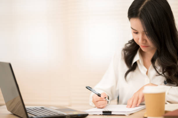 istock Asian working women wearing white shirts sitting at work desks. 1211278805