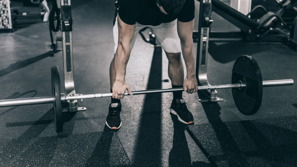 istock Determined man picking up barbell in gym 1211281480