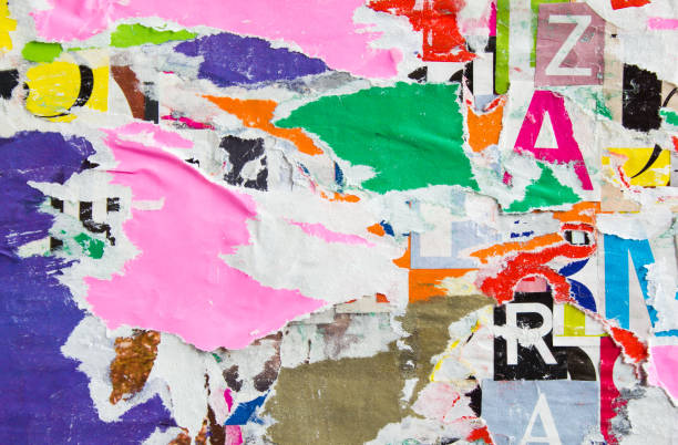 istock Old torn and peeling paper posters and placards layers on street wall billboard texture background. 1211281591