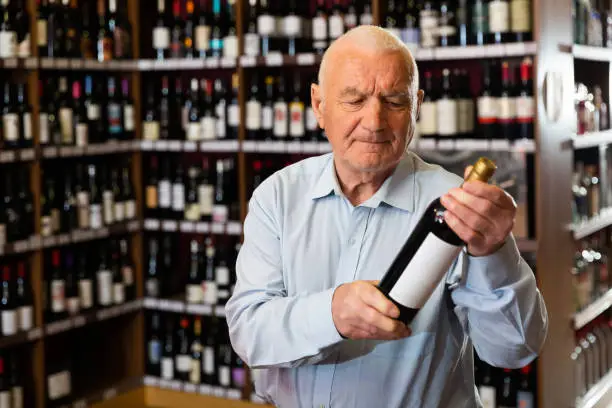 Portrait of senior man visiting winehouse in search of bottle of good wine