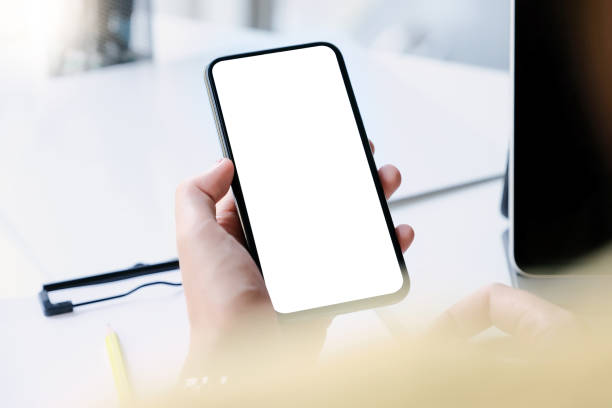 istock Woman hand holding smartphone on workplace. Blank screen mobile phone for graphic display montage 1211283813