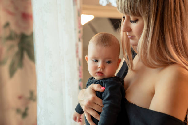 istock mother and child in black clothes stand at window 1211287578