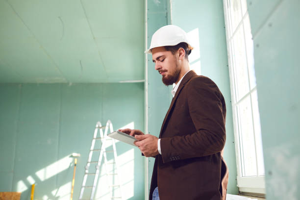 istock Foreman bearded man in a white helmet in a room at a construction site 1211289534