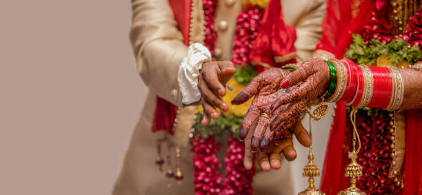 Very beautiful photo of a newly married Indian couple in ethnic attire offering flowers to God and taking blessings. Bride hands are decorated with henna design and colorful nuptial bangles. - Image. Traditional Indian Wedding Photo.
Concept of Ritual, Customs, Hindu Marriage, Vedic Marriage, Relationships, Husband Wife, Love Marriage, Arrange Marriage, Matrimony, Match making, Dowry marriage etc. depending on the vision of user.
Amazing photo of a traditional Indian wedding taking place wherein the bride and the groom are wearing ethnic Indian attire and are offering prasadam to fire god to receive blessings for their happy married life. Bride alongwith the dress is also wearing colorful bridal bangles and floral garland is worn by both bride and groom. bangle photos stock pictures, royalty-free photos & images