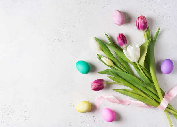 istock Tulips easter flat lay with pink and white flowers bouquet and eggs on white background. 1211294133