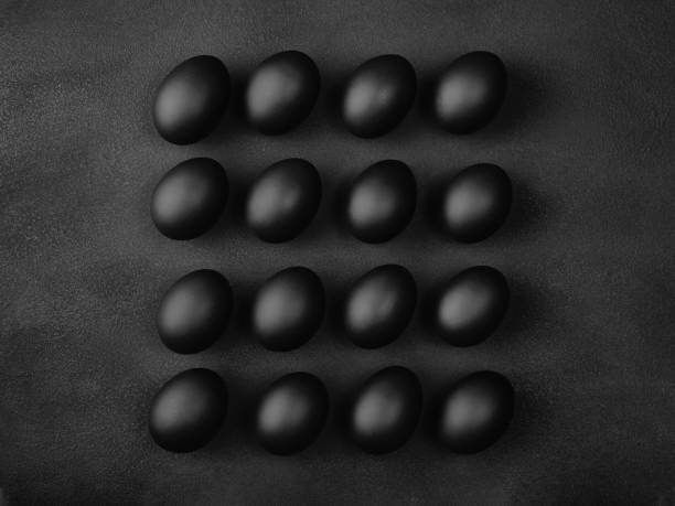 Square composition of sixteen black eggs on black background. Easter minimalist concept