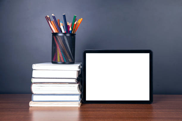 istock e-learning:Books and digital tablet on school desk with chalkboard 1211295598