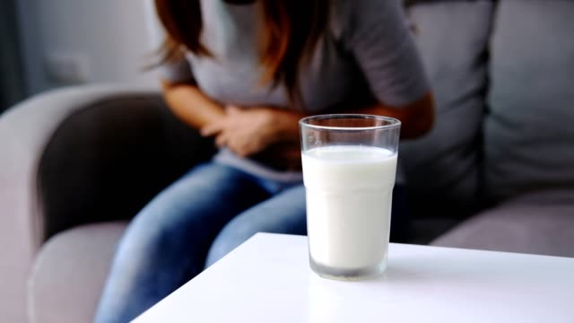Woman having bad stomach ache with a glass of milk, Lactose intolerance, health care concept