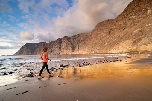 Mature Adult Woman Exercising on the Beach of  Playa de Los Gigantes, Canary Island Tenerife, Spain - stock photo